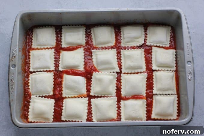 Easy Ravioli Lasagna 3 Layering frozen ravioli over sauce in a baking dish