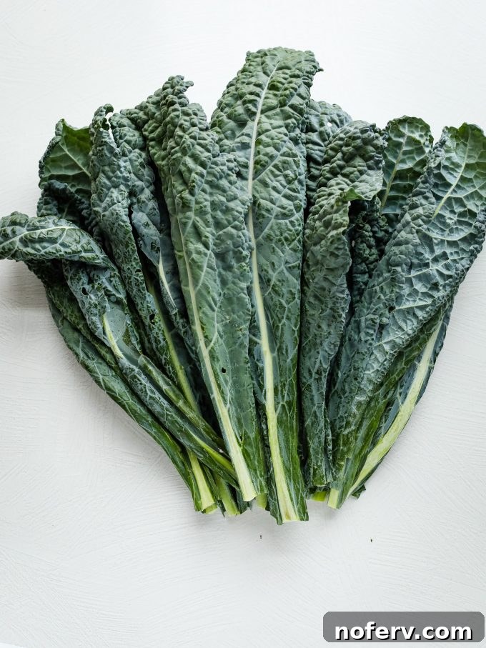 4 Reasons Why You've Misjudged Kale 2 Fresh Lacinato kale leaves on a rustic wooden surface, highlighting their deep green color and textured appearance.