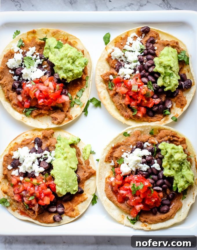 Vibrant vegetarian tostadas stacked on a plate, garnished with fresh cilantro and a dollop of guacamole, showcasing a quick and healthy meal.