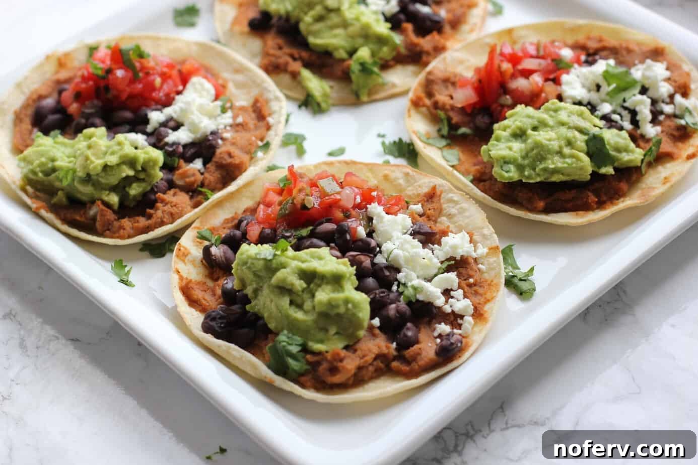 Four delicious tostadas served on a white plate, ready to be enjoyed.