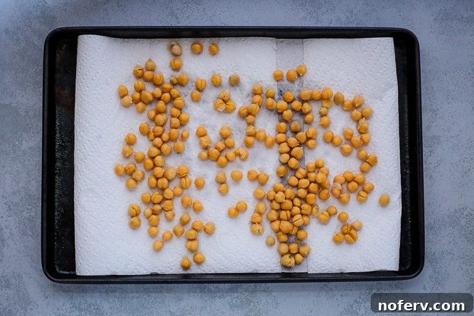 Rinsed and dried chickpeas spread on a paper towel to remove excess moisture.