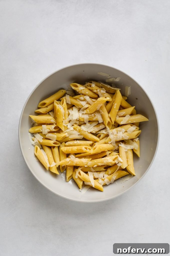 Uncooked pasta in a bowl, seasoned with olive oil and spices before air frying.