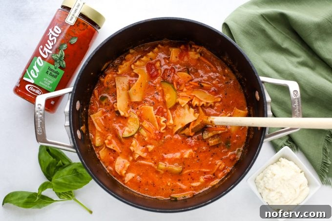 A large pot filled with rich, bubbling vegetarian lasagna soup, showing the noodles and vegetables simmering.