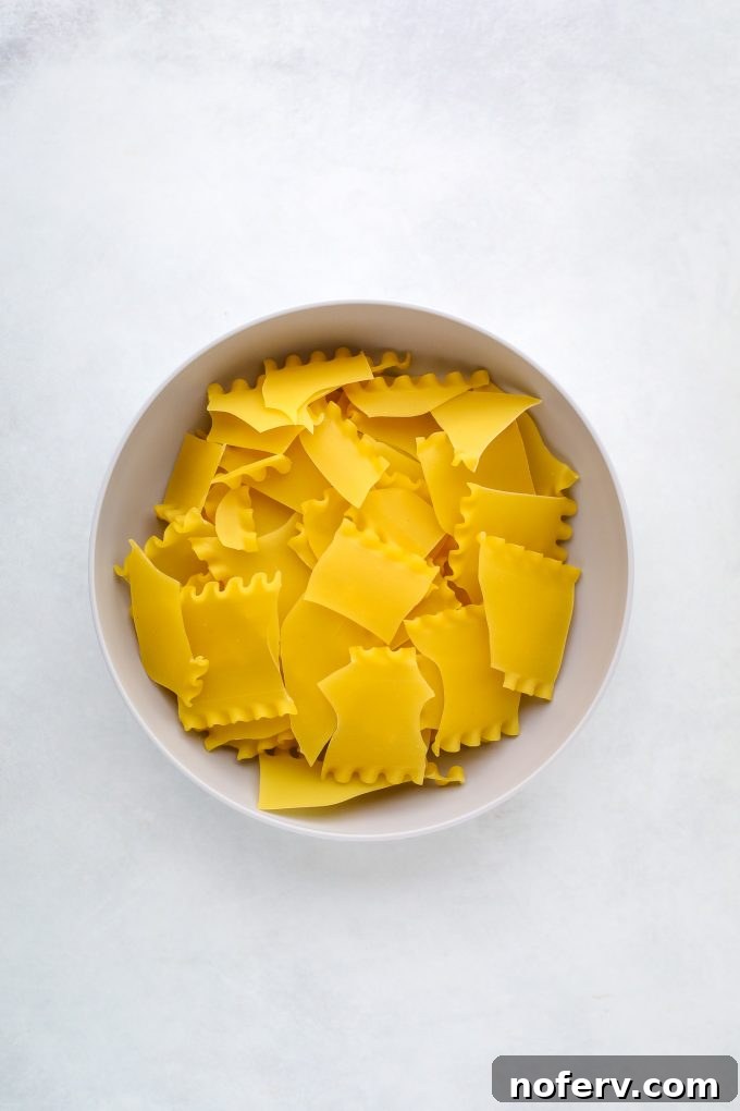 Uncooked lasagna noodles broken into smaller, bite-sized pieces, ready to be added to the soup pot.