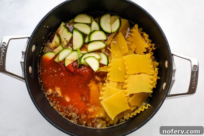 A vibrant bowl of vegetarian lasagna soup, rich with red sauce, pasta, and vegetables, ready for cheesy toppings.