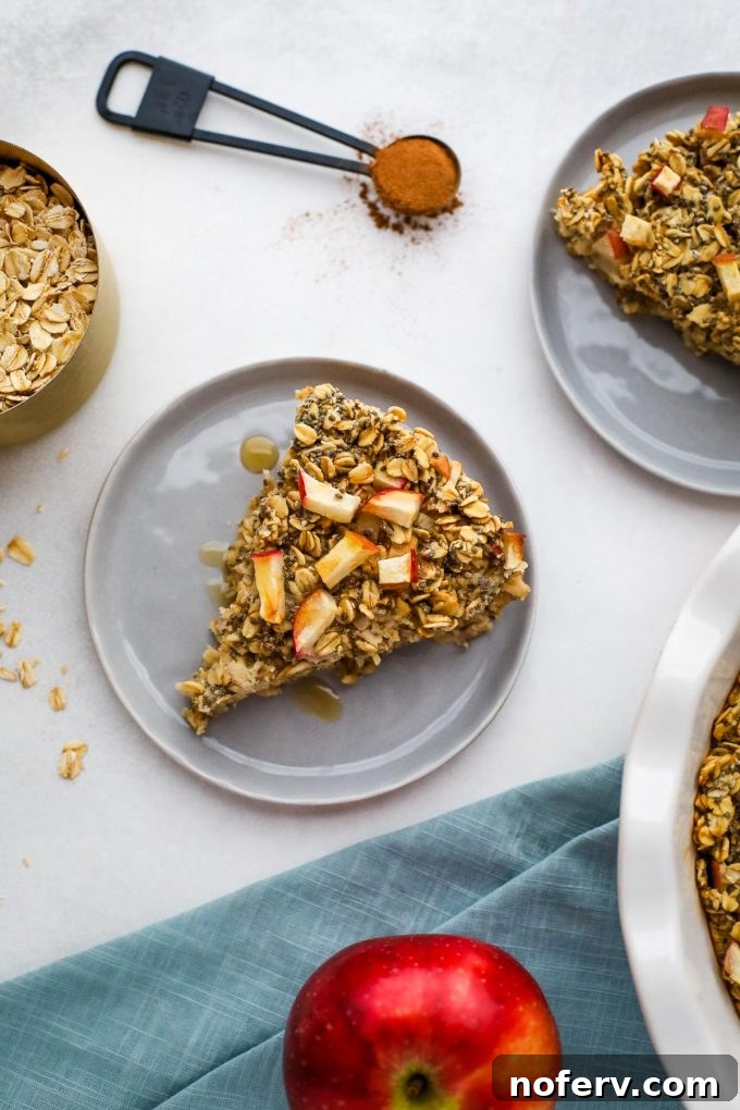 A slice of baked apple cinnamon oatmeal on a plate with fresh apple slices.