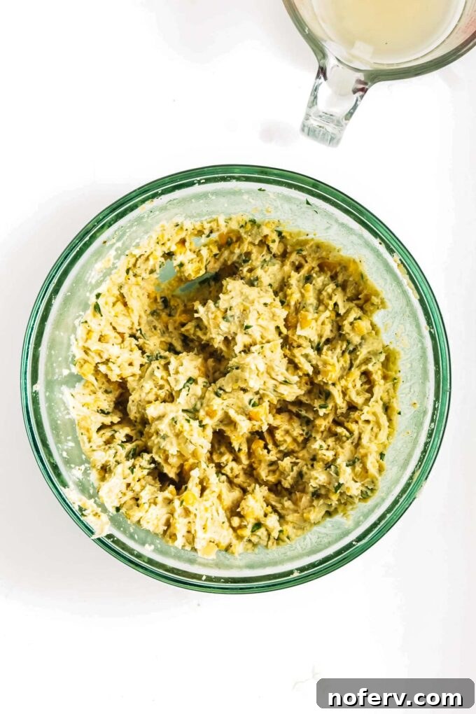 Golden Chickpea Burger Delights 7 Mashing ingredients in a bowl with a potato masher.