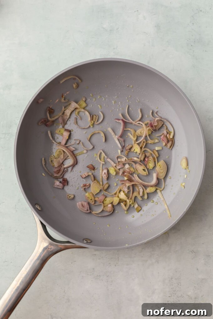 Heating olive oil with minced garlic and shallots in a skillet