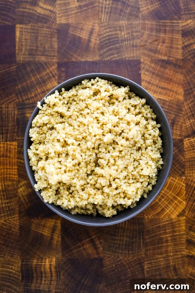 Roasted Butternut Squash and Quinoa Power Bowl 3 A bowl of fluffy cooked quinoa on a wooden table, ready for mixing into a salad