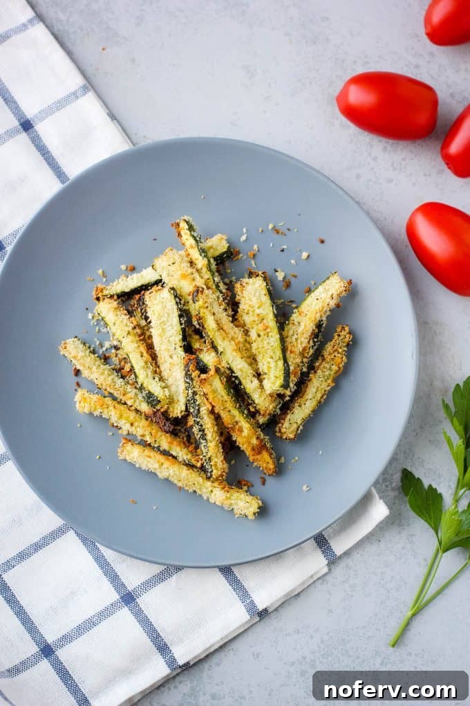 Crispy oven-baked zucchini fries on a baking sheet, ready to serve.