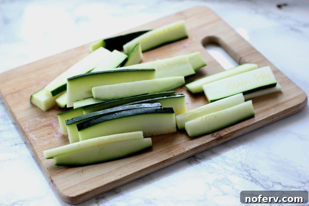 A fresh zucchini on a wooden cutting board, ready for slicing into fries.