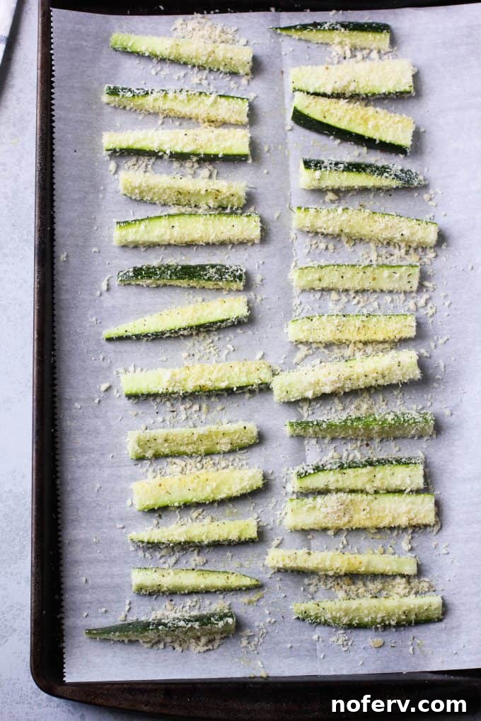 A baking tray filled with golden-brown oven-baked zucchini fries, perfectly crisp.