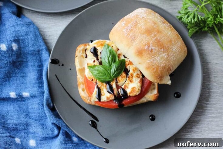 A delectable Crispy Halloumi Sandwich on a hearty ciabatta roll with tomato and balsamic glaze.