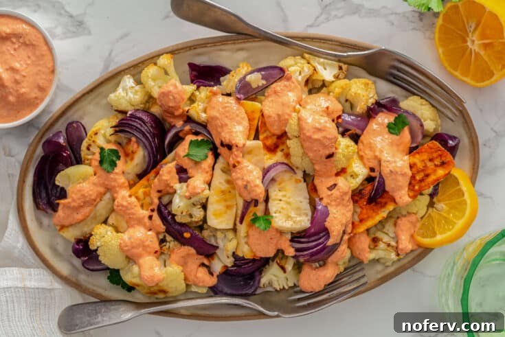 Sheet pan with roasted cauliflower and golden-brown halloumi cheese, a simple yet elegant vegetarian dinner.