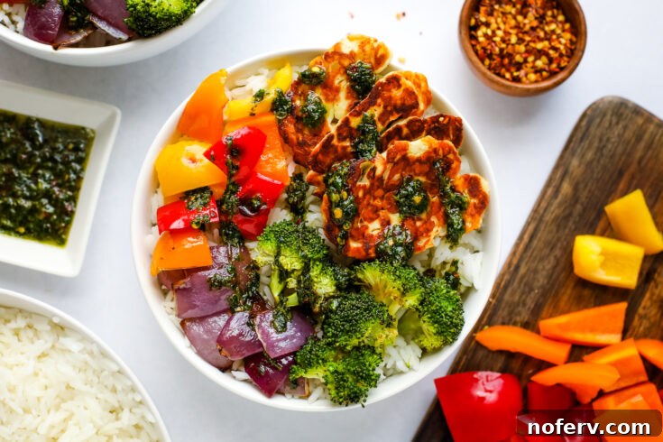 A colorful Halloumi Rice Bowl topped with crispy halloumi and an array of fresh vegetables.