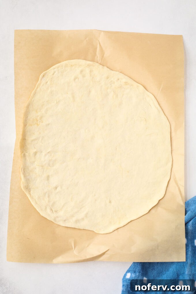 Vibrant Vegan Broccoli Pizza 7 Someone rolling out pizza dough on a floured surface with a wooden rolling pin