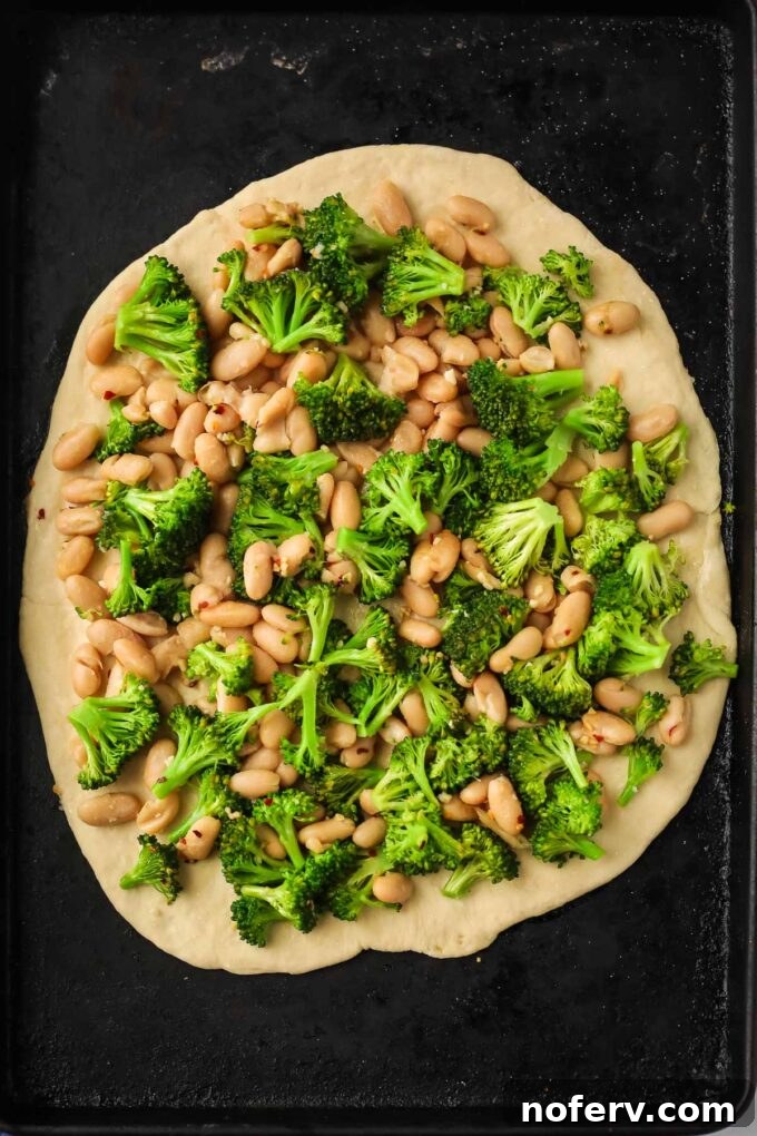 Vibrant Vegan Broccoli Pizza 8 Pizza dough on a baking sheet topped with the broccoli and white bean mixture