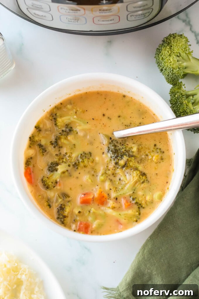 Close-up of a bowl of creamy Instant Pot broccoli cheddar soup with visible broccoli florets and melted cheese.