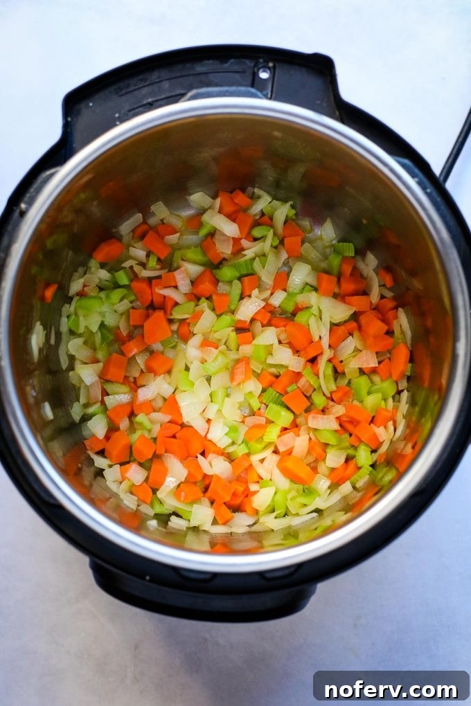 Diced onions, carrots, and celery sautéing in an Instant Pot with melted butter.